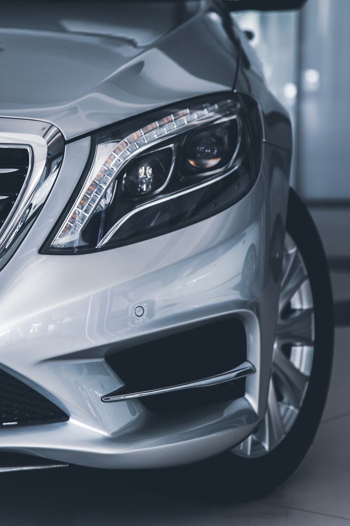 Detailed close-up of a luxurious silver car's headlight showcasing elegance and design.