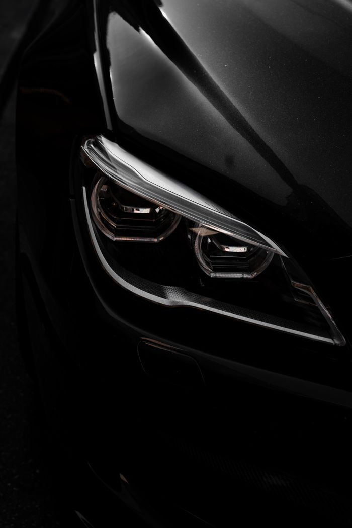 Detailed close-up of a sleek modern car headlight in Munich, showcasing elegant design and lighting.
