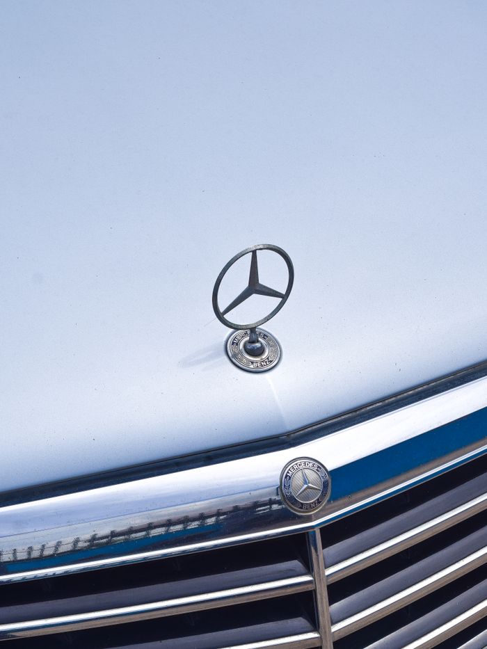 Detailed view of a car hood with a luxury emblem and grille, perfect for automotive themes.
