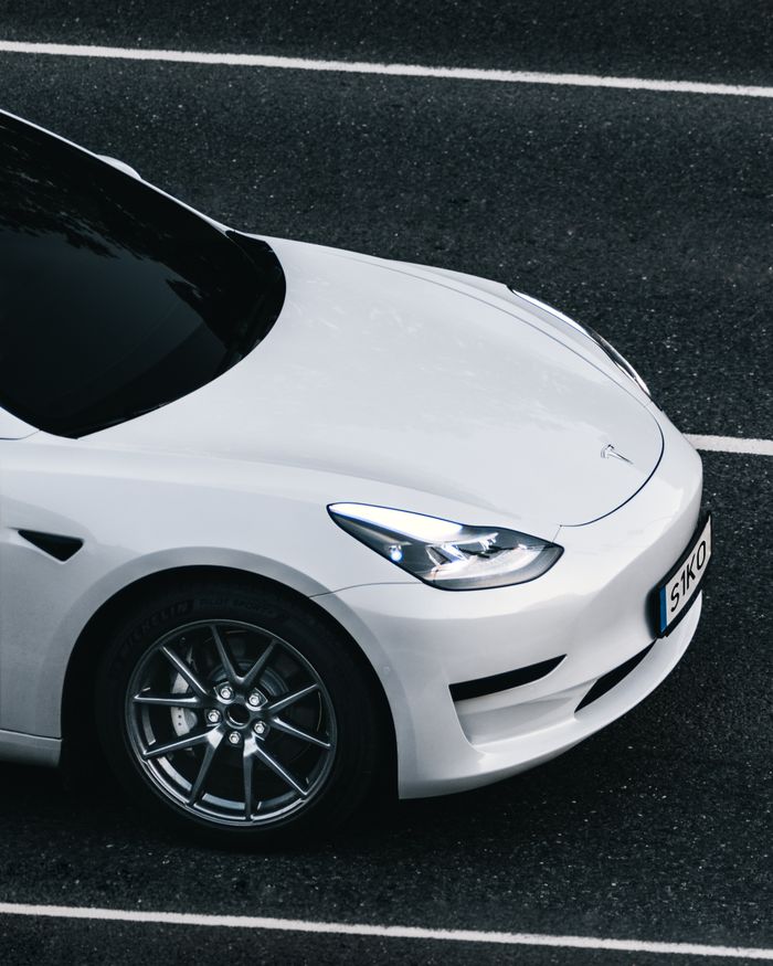 Top view of a sleek white Tesla electric car driving on a city street in Germany.
